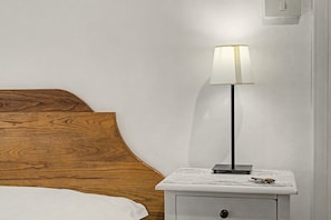 A bed with a wooden headboard, a bedside table with a lamp, and a small drawer. - 'Camera Petit' Apartment with Shared Garden, Wi-Fi and Air Conditioning (Venice)