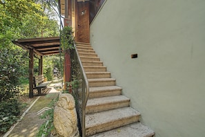 A staircase with stone steps leading to a wooden door, surrounded by greenery and a stone statue. - 'Camera Petit' Apartment with Shared Garden, Wi-Fi and Air Conditioning (Venice)