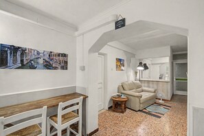 A hallway with a wooden bench, a beige armchair, and a small table with a lamp. There are two framed pictures on the walls. - 'Camera Petit' Apartment with Shared Garden, Wi-Fi and Air Conditioning (Venice)