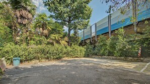 A parking area with a blue building in the background. - 'Camera Rose' Apartment with Shared Garden, Wi-Fi, and Air Conditioning (Venice)