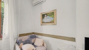 Une pièce d’angle avec un canapé, une petite table et un tableau encadré au mur.