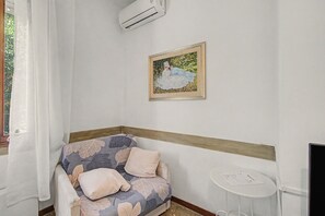 A corner room with a sofa, a small table, and a framed painting on the wall. - 'Camera Rose' Apartment with Shared Garden, Wi-Fi, and Air Conditioning (Venice)