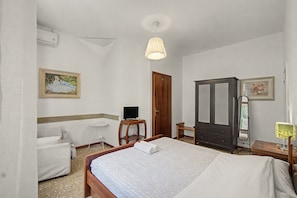 A bedroom with a bed, a chair, a desk, a wardrobe, and a mirror. - 'Camera Rose' Apartment with Shared Garden, Wi-Fi, and Air Conditioning (Venice)