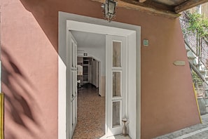 A hallway with a white door leading to a room, a small potted plant, and a sign on the wall. - 'Camera Rose' Apartment with Shared Garden, Wi-Fi, and Air Conditioning (Venice)