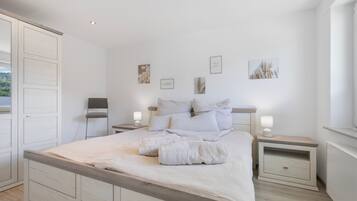 A bedroom with a large bed, two bedside tables, a wardrobe, and wall art.