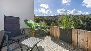 Ein Balkon mit Stuhl, kleinem Tisch und einer Holzlattenveranda mit Pflanzen.