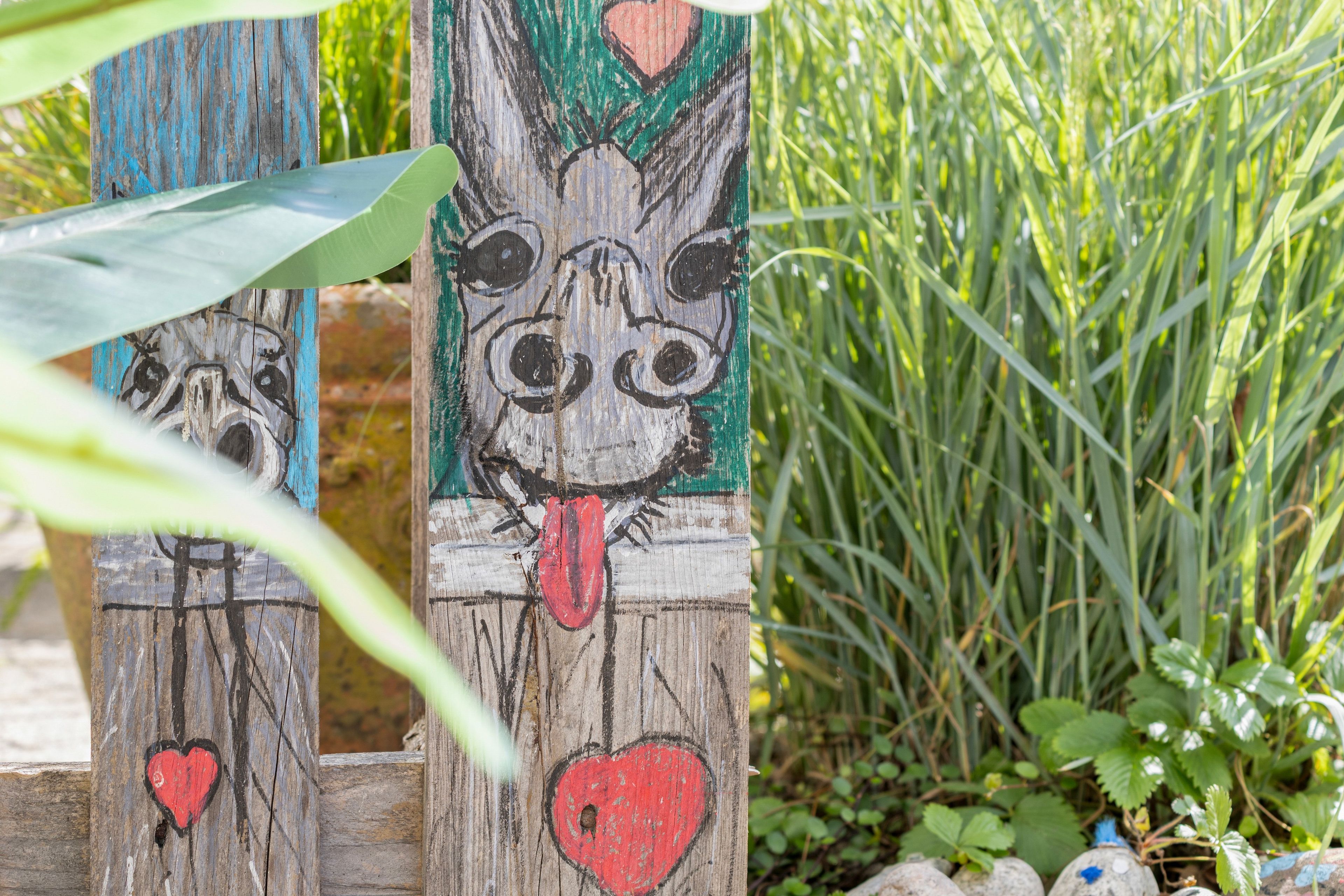 Una estructura de madera con rostros de animales pintados y corazones.