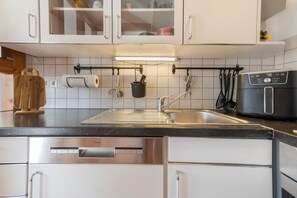 A kitchen with white cabinets, a stainless steel sink, and a black toaster oven. - Apartment 'Bei Walli' with Private Terrace and Wi-Fi (Kirchhundem)