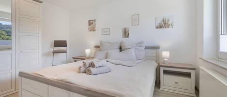 Une chambre à coucher avec un lit, des tables de chevet et des œuvres d’art murales.