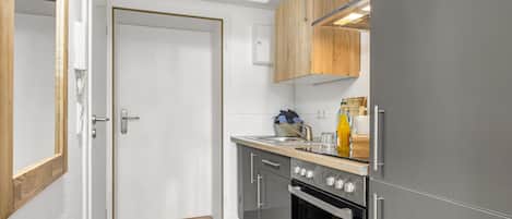 A modern kitchen with a built-in oven, a stainless steel sink, and wooden cabinets.
