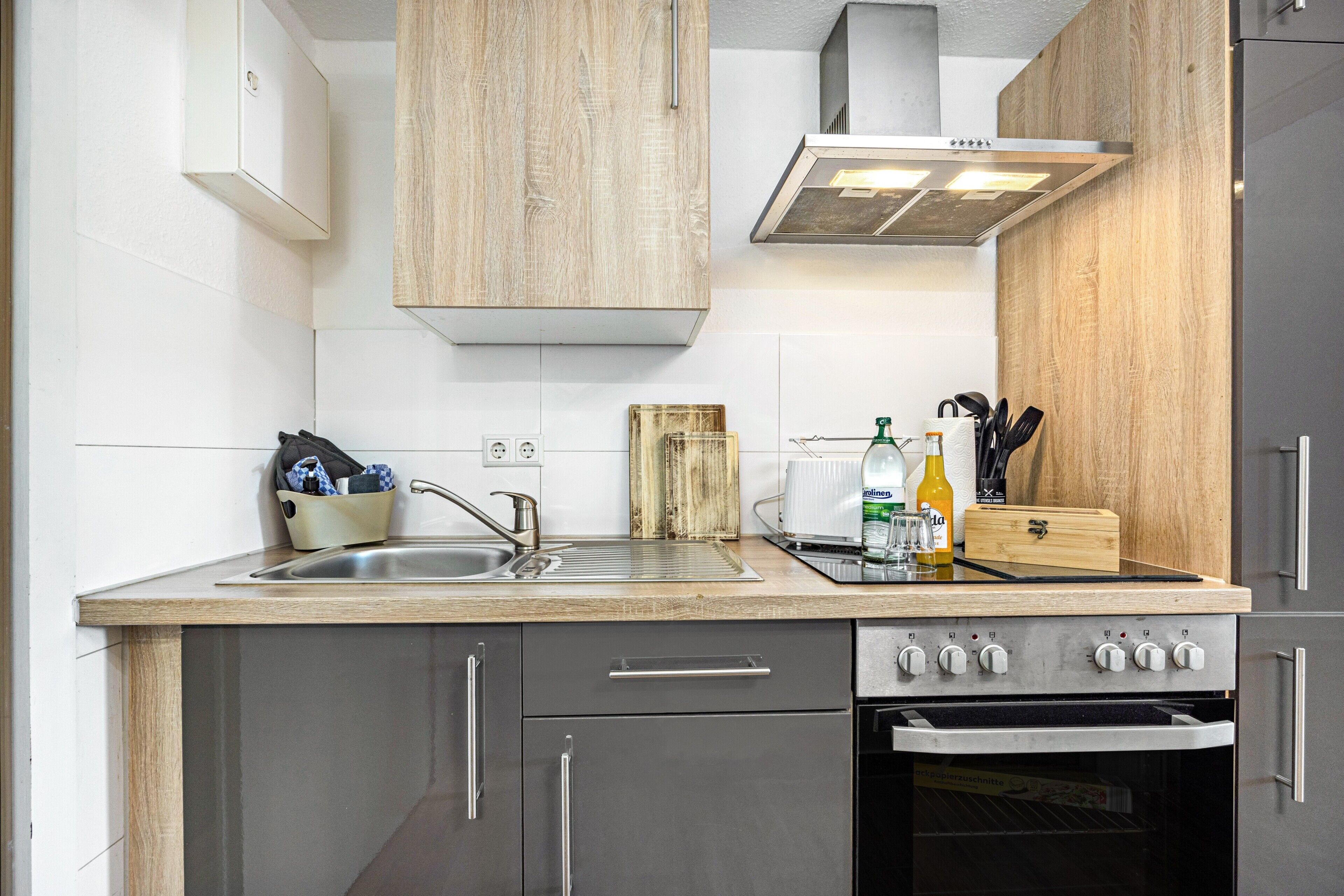 A modern kitchen with a stainless steel sink, a built-in oven, and a wooden countertop.