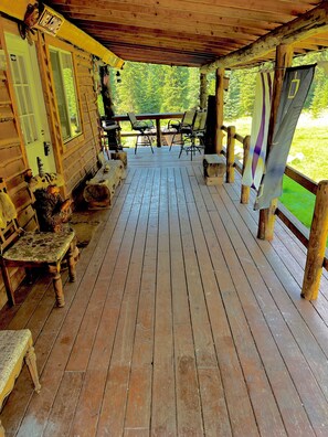 Eine Holzterrasse mit überdachter Sitzgruppe, einem Tisch und Stühlen.