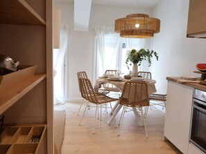 A dining area with wicker chairs, a round table, and a hanging light fixture. - Larrabide Boho Chic Apartment (Pamplona)