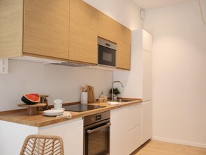 A modern kitchen with wooden cabinets, stainless steel appliances, and a wooden countertop.