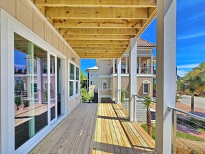 Una terrazza coperta all'aperto con pavimento in legno, ampie finestre e vista sugli edifici circostanti.