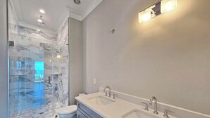 Et moderne badeværelse med en glasbrusekabine, et dobbeltvaskarrangement og et toilet.