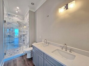 A modern bathroom with a glass shower enclosure, a double sink vanity, and a toilet. - Vista Del Mar: New Construction, Beach Views, Private Pool, Pet-Friendly, SGI Pl (St. George Island)