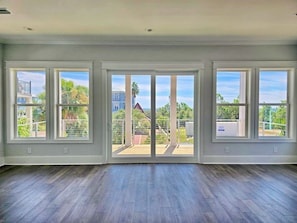 A spacious room with large windows and a view of a residential area. - Vista Del Mar: New Construction, Beach Views, Private Pool, Pet-Friendly, SGI Pl (St. George Island)