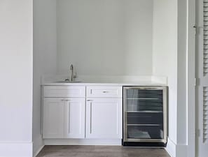 Eine kleine Küche mit weißen Schränken, einer eingebauten Spüle und einem Kühlschrank.
