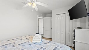 Una camera da letto con un letto, una ventola a soffitto, una televisione e un armadio.