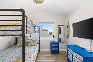 Een kamer met stapelbedden, een televisie, een dressoir en een raam met uitzicht.
