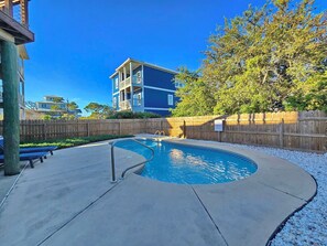A residential area with a swimming pool, wooden fence, and a multi-story building in the background. - The Lookout: North Cape, 3 Bedrooms, Pet-Friendly, Private Pool! Short walk to b (Cape San Blas)
