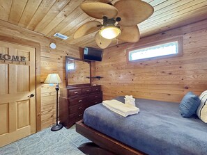 A wooden-paneled room with a bed, a dresser, a mirror, a ceiling fan, and a television. - The Lookout: North Cape, 3 Bedrooms, Pet-Friendly, Private Pool! Short walk to b (Cape San Blas)