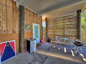 An outdoor patio area with a wooden fence, a barbecue grill, a table with chairs, and a trash bin. - The Lookout: North Cape, 3 Bedrooms, Pet-Friendly, Private Pool! Short walk to b (Cape San Blas)