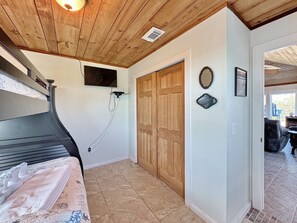 A bedroom with a bed, a wooden ceiling, a television mounted on the wall, and a wooden door. - The Lookout: North Cape, 3 Bedrooms, Pet-Friendly, Private Pool! Short walk to b (Cape San Blas)