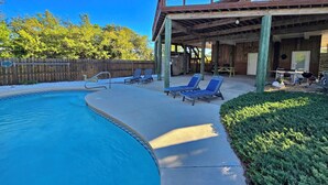 Ein Pool mit Liegestühlen, eine überdachte Terrasse und eine Holzterrasse.