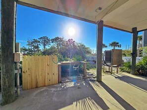 An outdoor patio area with a wooden fence, a concrete floor, and a view of trees and a clear sky. - The Lookout: North Cape, 3 Bedrooms, Pet-Friendly, Private Pool! Short walk to b (Cape San Blas)