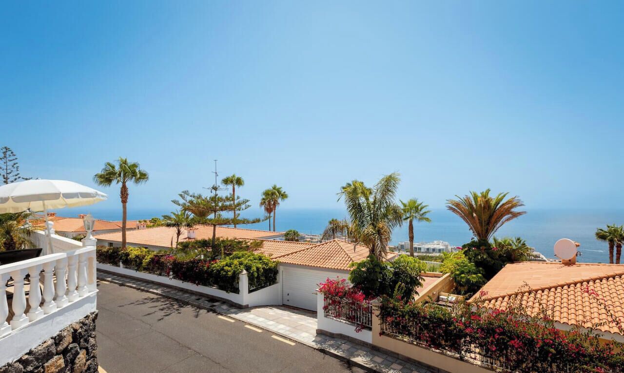 Un quartier résidentiel situé sur la côte, offrant une vue dégagée sur la mer, avec une clôture blanche et une antenne parabolique installée sur un immeuble.