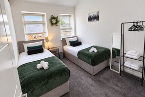 A hotel room with two beds, a mirror, a towel rack, and a view of the cityscape. - 3 Bed House-Sleeps 8-Families-Contractors-NHS-Garden-Parking-Fast WiFi (Willenhall)
