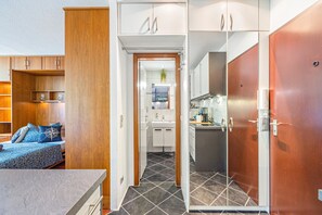 Habitación de hotel compacta con cama, kitchenette pequeña y baño.