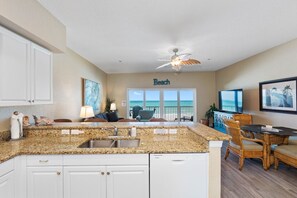 A kitchen with granite countertops, white cabinetry, and a built-in dishwasher. - Ocean Side Beach Front Penthouse! (Indian Rocks Beach)