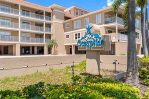Ein mehrstöckiges Hotel mit einem Schild, auf dem 'Oceanside 102' steht, und Balkonen.