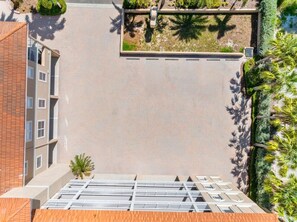 Eine Dachterrasse mit Metallgeländer, einem kleinen Gartenbereich und Blick auf angrenzende Gebäude.