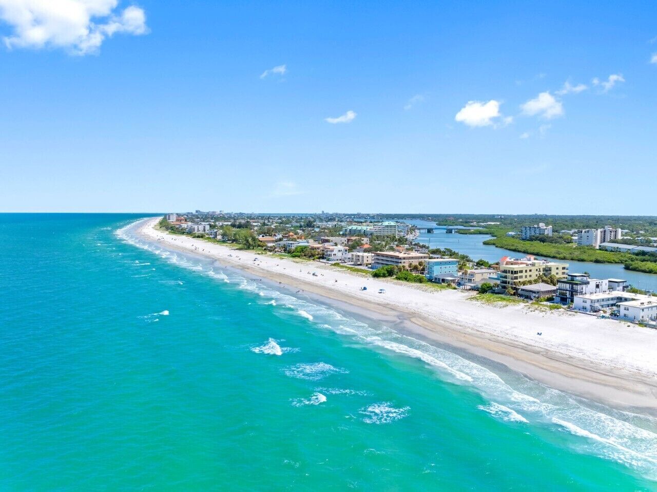 A coastal cityscape with a beach, buildings, and a clear sky.
