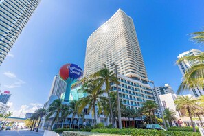 A modern hotel with a curved facade, palm trees, and a prominent sign for the hotel. - Waterfront Oasis With Resort Amenities (Hollywood)