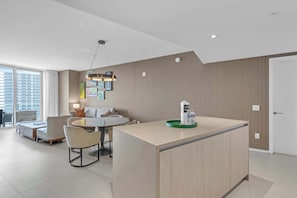 A modern interior with a dining area, a sofa, and a kitchen island with a water dispenser. - Waterfront Oasis With Resort Amenities (Hollywood)