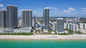 A coastal cityscape with high-rise buildings, a beach, and clear turquoise waters. - Waterfront Oasis With Resort Amenities (Hollywood)
