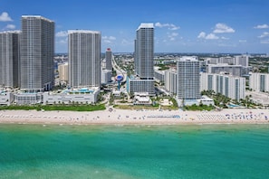 A coastal cityscape with high-rise buildings, a beach, and clear turquoise waters. - Waterfront Oasis With Resort Amenities (Hollywood)