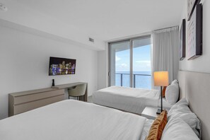 A hotel room with two beds, a desk, a chair, a TV, and a window with a view of the sea. - Waterfront Oasis With Resort Amenities (Hollywood)