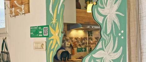 A mirror with a floral design, a clock, and a welcome sign with QR code.
