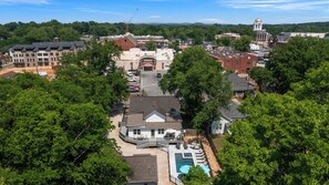 Ett bostadsområde med ett stort hus som har en swimmingpool och är omgivet av träd och andra hus.