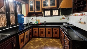A kitchen with wooden cabinets, a black countertop, a water dispenser, and a patterned floor.