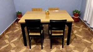 A dining area with a wooden table, four chairs, and two potted plants.