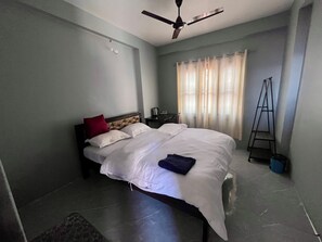 A bedroom with a bed, a ceiling fan, a window with curtains, and a ladder.