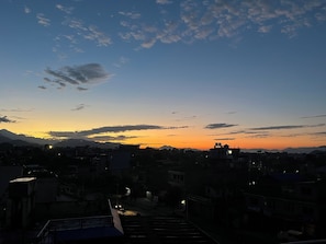 Une vue sur une ville au crépuscule, avec des bâtiments se détachant en silhouette sur un ciel au coucher du soleil.