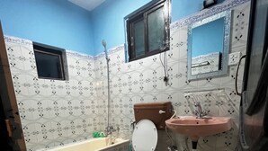 A bathroom with a toilet, sink, bathtub, and a mirror.